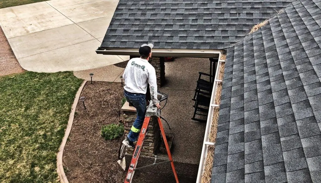 Construction worker climbing up ladder towards residential roof