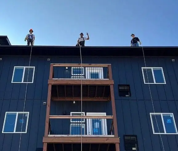 Construction workers waving hi from the top of an apartment building