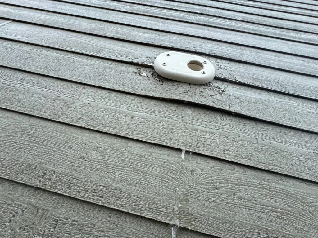 View from below of intake/exhaust pipe where showing siding damage for warranty claim