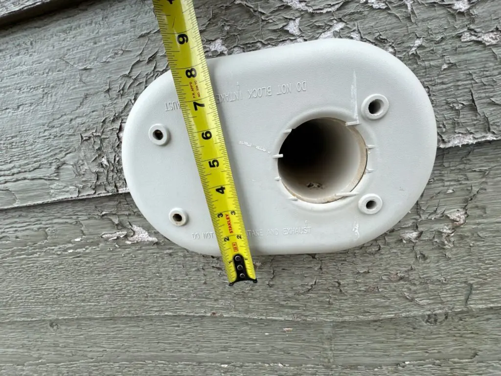 Tape measure being used to measure pipe where siding damage is located for warranty claim
