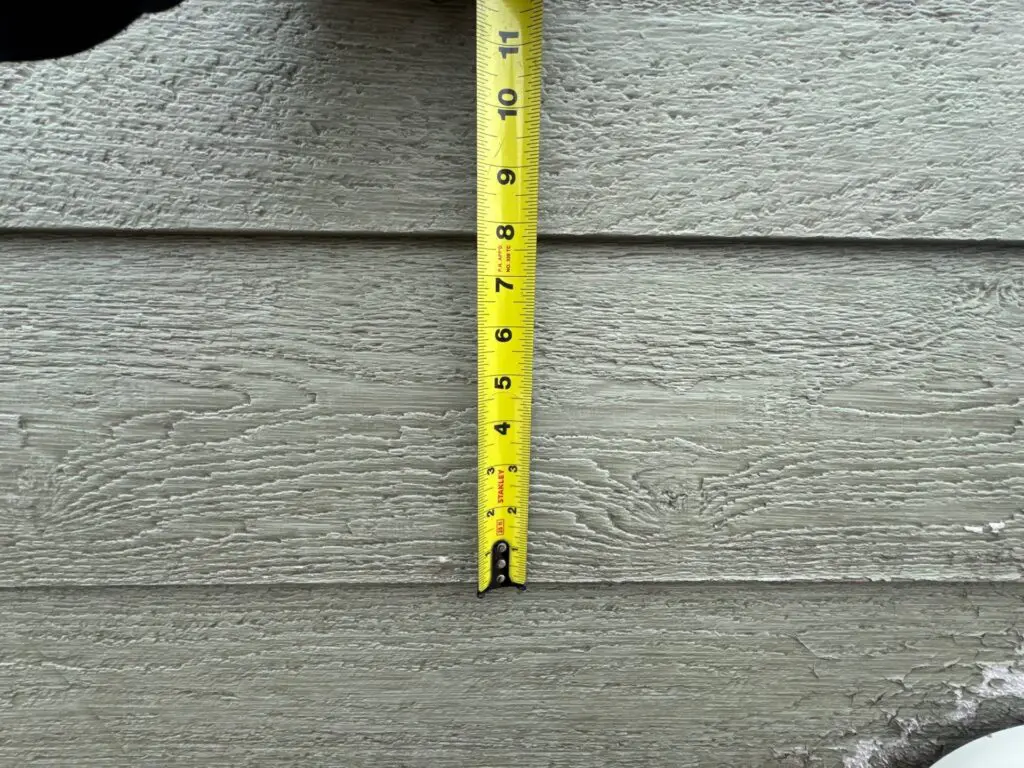 Tape measure being used to show size of siding for warranty claim