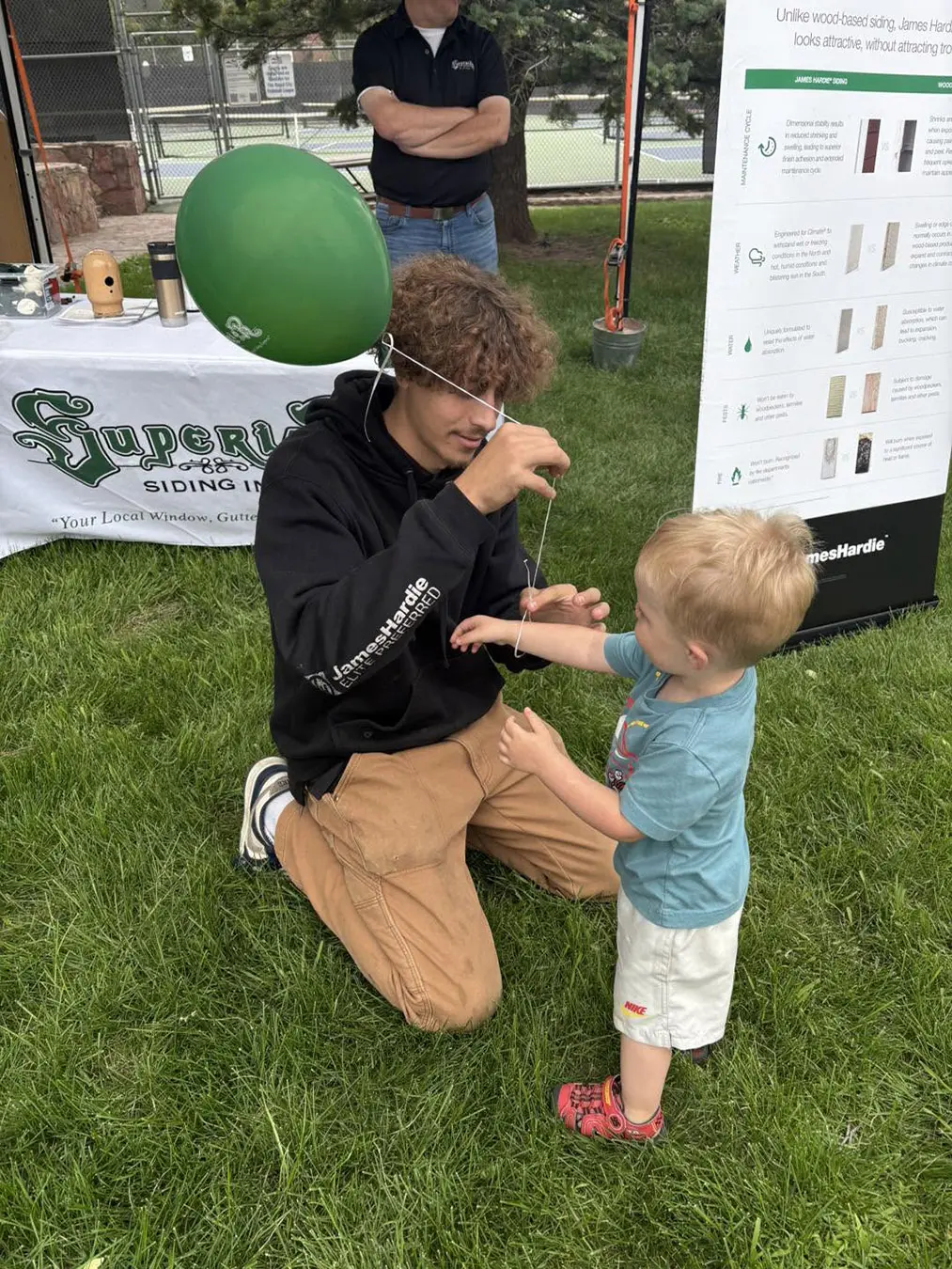 Crew member dillon giving a balloon to a child at the West Blvd Craft Fair