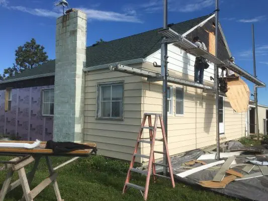 Construction worker repairing siding on a house