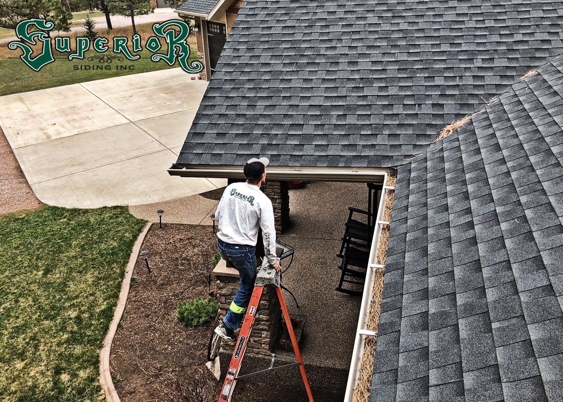 Construction worker climbing up ladder towards residential roof