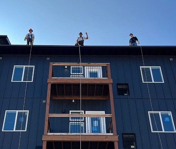 Construction workers waving hi from the top of an apartment building