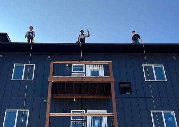 Construction workers waving hi from the top of an apartment building