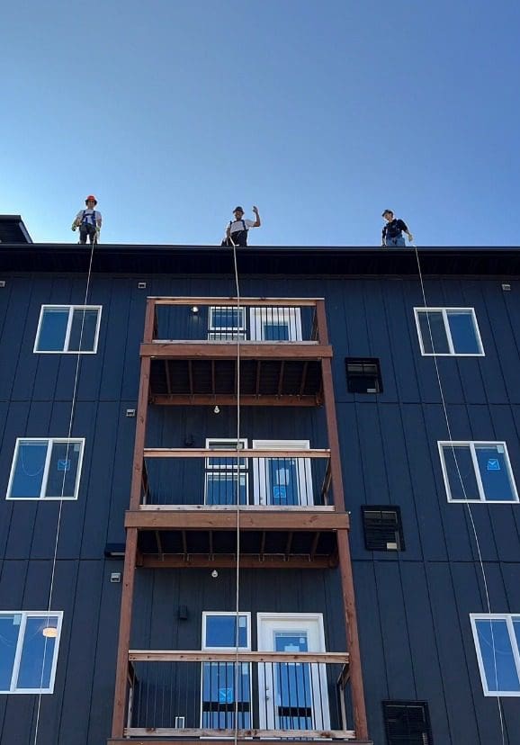 Construction workers waving hi from the top of an apartment building