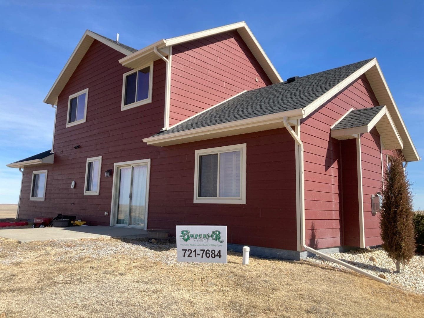 House with new red siding with Superior Siding sign in front