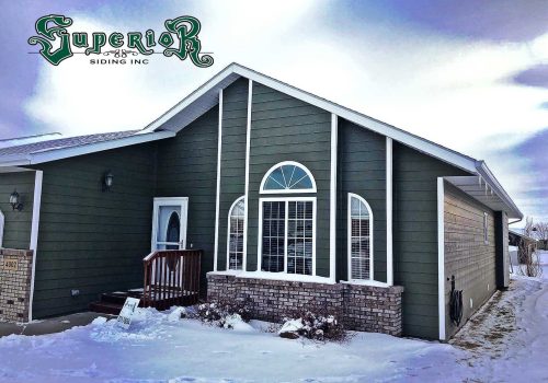 House with new green siding with snow on the ground